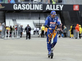 Fernando Alonso, of Spain, rides his scooter back to the garage after rain ended a practice session for the Indianapolis 500 IndyCar auto race at Indianapolis Motor Speedway, Sunday, May 19, 2019 in Indianapolis.