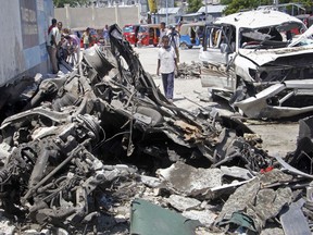 Somalis walk near the wreckage after a suicide car bomb attack in the capital Mogadishu, Somalia Wednesday, May 22, 2019. A police spokesman said the attack killed at least six people and injured more than a dozen, while Islamic extremist group al-Shabab claimed responsibility for the blast, saying it targeted vehicles carrying government officials.