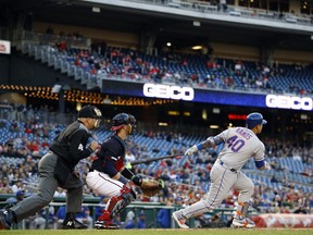 New York Mets' Wilson Ramos, right, watches his grand slam in front of Washington Nationals catcher Yan Gomes and home plate umpire Jeff Nelson during the first inning of a baseball game Tuesday, May 14, 2019, in Washington.