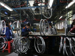 FILE - In this March 4, 2011, file photo, workers from the Dahon, the world's largest maker of folding bicycles, assembles the bicycle wheels in Shenzhen, a city of southern China. The latest round of China tariff hikes, which went into effect Friday, May 10, 2019. will hit a range of consumer goods, including bicycles, luggage, furniture and seafood.