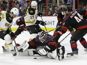 Boston Bruins' David Pastrnak (88), of the Czech Republic, and Patrice Bergeron (37) look to score on Carolina Hurricanes goalie Curtis McElhinney while Hurricanes' Calvin de Haan (44) defends during the first period in Game 4 of the NHL hockey Stanley Cup Eastern Conference final series in Raleigh, N.C., Thursday, May 16, 2019.
