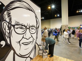 A Berkshire Hathaway shareholder arranges her shopping next to a large drawing of Chairman and CEO Warren Buffett, during a shareholders shopping event in Omaha, Neb., Friday, May 3, 2019, one day before Berkshire Hathaway's annual shareholders meeting. An estimated 40,000 people are expected in town for the event, where Chairman and CEO Warren Buffett and Vice Chairman Charlie Munger will preside over the meeting and spend hours answering questions.