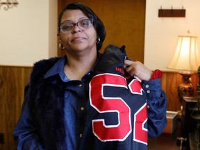 In this Feb. 13, 2019 photo, JoAnne Atkins-Ingram drapes her son's old Neptune High School football jersey over her shoulder in her attorney's office in Avon-by-the-Sea, N.J. Her 19-year-old son, Braeden Bradforth, died in August 2018 about an hour and a half after football practice at Garden City Community College in Garden City, Kan. New Jersey's U.S. House delegation is seeking an independent investigation into Bradforth's death.