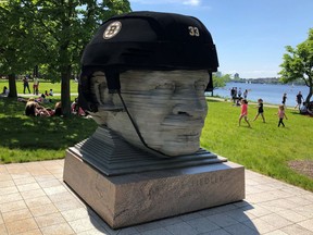 In this May 27, 2019, photo provided by Michael Nichols, a giant Boston Bruins helmet rests atop a statue of the late conductor Arthur Fiedler on the Charles River Esplanade park Monday, May 27, 2019, to cheer on the team in Game 1 of the NHL hockey Stanley Cup finals. The nonprofit Esplanade Association installed the helmet, which has a circumference of 17 feet (5 meters).