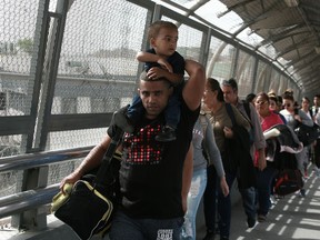 In this April 29, 2019, photo, Cuban migrants are escorted by Mexican immigration officials in Ciudad Juarez, Mexico, as they cross the Paso del Norte International bridge to be processed as asylum seekers on the U.S. side of the border. Burgeoning numbers of Cubans are trying to get into the U.S. by way of the Mexican border, creating a big backlog of people waiting on the Mexican side for months for their chance to apply for asylum.