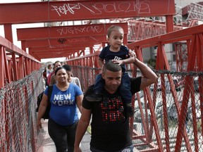 In this April 29, 2019, photo, Cuban migrants are escorted in Ciudad Juarez, Mexico, by Mexican immigration officials as they cross the Paso del Norte International bridge to be processed as asylum seekers on the U.S. side of the border. U.S. authorities have been telling asylum seekers that they are at capacity and to return when space opens up, a hands-off approach that has created haphazard and often-dubious arrangements in Mexico.