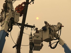 FILE - In this Nov. 9, 2018 file photo, Pacific Gas & Electric crews work to restore power lines in Paradise, Calif. Some investors call PG&E the first climate change bankruptcy. It filed for Chapter 11 protection earlier this year due to potential liabilities piling up following devastating wildfires in northern California.
