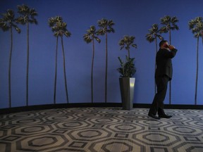 FILE - In this May 4, 2018, file photo a man talks on the phone in a hallway adorned with the palm tree-printed wallpaper at a hotel near the Los Angeles International Airport in Los Angeles. U.S. regulators are proposing new measures intended to thwart billions of annoying robocalls received by Americans each year. The rising volume of unwanted calls in the last few years has created pressure on Congress, regulators and phone companies to do something to act.