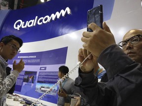 FILE - In this Nov. 6, 2018 file photo, attendees look at the latest technology from Qualcomm at the China International Import Expo in Shanghai. Qualcomm's stock is tumbling before Wednesday's market open on May 22, 2019, after a federal judge ruled that the company unlawfully stifled cellphone chip market competition and charged excessive licensing fees.