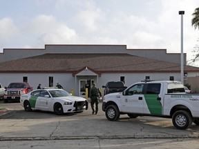 FILE - In this June 23, 2018 file photo, a U.S. Border Patrol Agent walks between vehicles outside the Central Processing Center in McAllen, Texas. U.S. border agents have temporarily closed their primary facility for processing migrants in South Texas one day after authorities say a 16-year-old died after being diagnosed with the flu at the facility. In a statement released late Tuesday, May 21, 2019, U.S. Customs and Border Protection said it would stop detaining migrants at the processing center in McAllen, Texas. CBP says "a large number" of people in custody were found Tuesday to have high fevers.