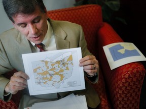 FILE - In this April 11, 2019 file photo, David Niven, a professor of political science at the University of Cincinnati holds a map displaying the wide disparity of Ohio congressional district office locations, with orange locations representing areas whose office are found outside it's own district's bounds, in Cincinnati. A federal court ruled Friday, May 3 that Ohio's congressional map is unconstitutional and ordered a new one be drawn for the 2020 elections.