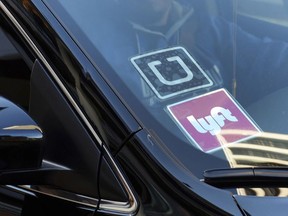 FILE - In this Jan. 12, 2016, file photo, a ride share car displays Lyft and Uber stickers on its front windshield in downtown Los Angeles. One in six Uber and Lyft drivers in the New York City and Seattle areas are driving vehicles with outstanding recalls, according to Consumer Reports.  But taking a taxi or limousine isn't necessarily a safer option as nearly a quarter of traditional for-hire vehicles in New York City also have outstanding recalls, Consumer Reports said.