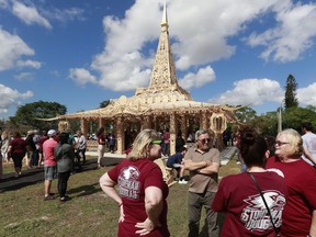 FILE - In this Feb. 14, 2019, file photo, people gather around the "Temple of Time" in honor of the 17 that were killed during the Marjory Stoneman Douglas High School shooting in 2018 in Coral Springs, Fla. The temple built as a memorial to the 17 victims of a Florida high school mass shooting is to be burned to the ground in a symbolic gesture of healing.