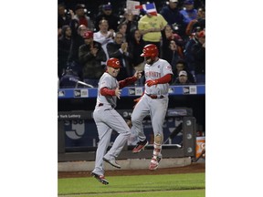 Cincinnati Reds' Eugenio Suarez, right, celebrates with third base coach J.R. House after hitting a home run during the sixth inning of the team's baseball game against the New York Mets on Tuesday, April 30, 2019, in New York.