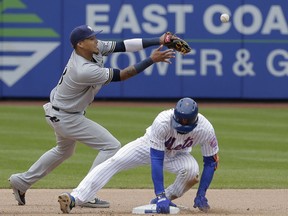 Milwaukee Brewers shortstop Orlando Arcia, left, can't grab the ball as New York Mets' Amed Rosario slides safely into second base during the seventh inning of the MLB baseball game at Citi Field, Sunday, April 28, 2019, in New York. Rosario advanced to second base on a fielding error.