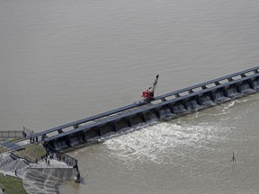 FILE - In this March 8, 2018 file photo workers open the gates of the Bonnet Carre spillway, a river diversion structure, which diverts water from the rising Mississippi River, left, to Lake Pontchartrain, in Norco, La. The Army Corps of Engineers' New Orleans office is asking to open the historic flood control structure above New Orleans for the second time in one year. The National Weather Service says continued rains in the Midwest and Ohio Valley and floodwaters from the upper Mississippi River are heading down the Mississippi.