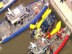 In this image made from video provided by WABC-TV, harbor units from the New York City police and fire departments work to secure a helicopter to the dock after it crashed in the Hudson River, Wednesday, May 15, 2019 in New York. WABC reports that the pilot was ok and that there were no passengers on the aircraft. (WABC-TV via AP)