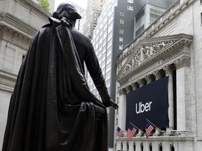 The statue of George Washington, on the steps of Federal Hall, overlooks the Uber banner hanging on the facade of the New York Stock Exchange, Friday, May 10, 2019. The world's largest ride-hailing service reached a major milestone Thursday when Uber priced its long-awaited initial public offering at $45 price per share to set the stage for its stock to begin trading Friday morning.