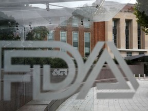 FILE - This Thursday, Aug. 2, 2018, file photo shows the U.S. Food and Drug Administration building behind FDA logos at a bus stop on the agency's campus in Silver Spring, Md. The FDA said Thursday, May 2, 2019, that a type of breast implant linked to a rare form of cancer will be allowed to stay on the market.