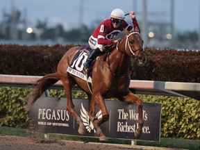 FILE - In this Jan. 27, 2018, file photo, jockey Florent Geroux rides Gun Runner (10) past the finish line to win the Pegasus World Cup Invitational horse race, at Gulfstream Park in Hallandale Beach, Fla. Billionaire Frank Stronach made his money in auto parts and wanted to put it into horse racing. It was his idea in 2016 to launch the Pegasus World Cup at Gulfstream Park in Florida, which now has the biggest purse in the world at $16 million.