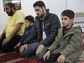 In this Thursday, March 21, 2019, photo, Sadek Ahmed, second from right, prays with his sons Adel, 9, right, and Mutaz, 7, second from left, before heading to his evening job in the Brooklyn borough of New York. Their mother, Amena Abdulkarem, is stuck in Yemen with her two younger sons, the boys' brothers. Their family's situation is representative of the toll that the Trump administration's almost-forgotten travel ban has taken on an untold number of families.