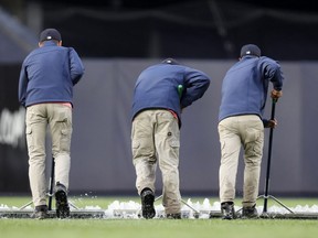Groundskeepers use squeegees to remove water from the field at Yankee Stadium before a baseball game between the New York Yankees and the Baltimore Orioles, Monday, May 13, 2019, in New York. The game was postponed until Wednesday afternoon.