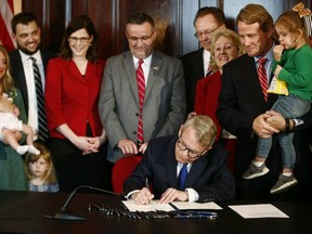 FILE- In this April 11, 2019 file photo, Gov. Mike DeWine signs a bill imposing one of the nation's toughest abortion restrictions, in Columbus, Ohio. Planned Parenthood and Ohio abortion clinics have sued to prevent the state's restrictive abortion law from taking effect. The complained filed Wednesday, May 15 in federal court in Columbus says the ban of abortions after the first detectable fetal heartbeat is unconstitutional and would prohibit nearly all abortions in Ohio. A detectable heartbeat can come as early as five or six weeks into pregnancy, before many women know they're pregnant.