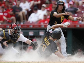 Pittsburgh Pirates' Adam Frazier (26) scores against Cincinnati Reds catcher Tucker Barnhart, left, on a two-run double by Bryan Reynolds off relief pitcher David Hernandez in the eighth inning during the first baseball game of a doubleheader, Monday, May 27, 2019, in Columbus.