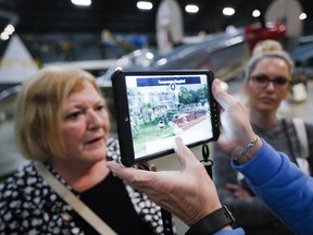In this Friday, April 26, 2019 photo, Deane Sager, of Louisville, off camera, and his wife Cathy, left, use a Histopad tablet to view scenes from operations on the western front of World War II at the The National Museum of the U.S. Air Force, in Dayton, Ohio. French-developed technology making its U.S. debut this month will allow new views of the D-Day invasion 75 years ago that began the liberation of France and helped end World War II. The National Museum of the U.S. Air Force near Dayton begins its D-Day commemorations May 13 with military-veteran paratroopers dropping from a vintage plane flying overhead, new exhibits and movies about the June 6, 1944, attack on heavily fortified German positions guarding the coastline.