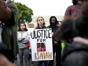 FILE - In this May 3, 2019 file photo, a protestor holds a sign at the Edmond Police Department during a Black Lives Matter protest rally honoring the life of Isaiah Lewis in Edmond, Okla. The parents of Lewis, a black teenager who was naked and unarmed when he was fatally shot by suburban Oklahoma City police, want to meet with the police chief, mayor and other city officials to get their take on what transpired.