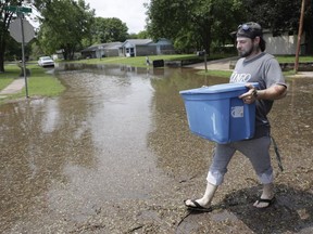 Brian Dubuc removes items from his home as water approaches in the Meadow Valley neighborhood of Sand Springs, Okla., Thursday, May 23, 2019.