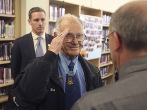 FILE - In this Nov. 8, 2013 file photo, Medal of Honor recipient Bob Maxwell, center, salutes at a ceremony at Bend High School in Bend, Ore., where he received a commemorative set of postage stamps honoring the few surviving Medal of Honor recipients from World War II. Maxwell, the nation's oldest Medal of Honor recipient, has died in Oregon more than seven decades after grabbing a blanket and throwing himself on a German hand grenade in France to save his squad mates. He was 98. Maxwell died Saturday, May 11, 2019, in Bend, Ore.