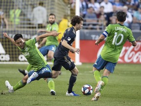 Philadelphia Union's Brenden Aaronson, center, slips between Seattle Sounders' Kim Kee-Hee, left, and Nicolas Lodeiro with the ball during the first half of an MLS soccer match Saturday, May 18, 2019, in Chester, Pa.