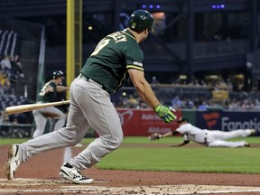 Pittsburgh Pirates third baseman Jung Ho Kang, rear, dives for but can't come up with a ball hit down the line by Oakland Athletics' Josh Phegley, foreground, with bases loaded off Pirates starting pitcher Joe Musgrove during the second inning of a baseball game in Pittsburgh, Friday, May 3, 2019. Three runs scored on the double, and Phegley had a career-high eight RBIs to lead the Athletics to a 14-1 win.