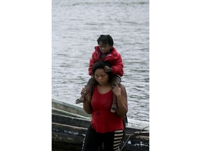 In this May 25, 2019 photo, a migrant woman carries her child on her shoulders after wading across the Tuquesa river in Bajo Chiquito, Darien province, Panama. The woman and her child had walked for many days in the jungle before arriving in Bajo Chiquito.