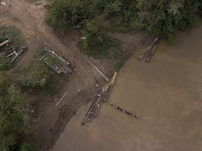 In this May 10, 2019, a group of migrants are boated across the Chucunaque river as they arrive in Peñitas, Darien Province, Panama. Darien's rivers can rise suddenly and furiously, and in recent weeks at least 10 migrants were reportedly swept to their deaths.