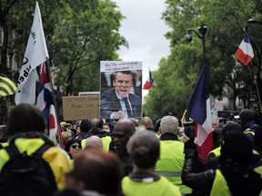 Yellow Vest protestors, one carrying a placard with a picture and a quote of French President Macron "Let Them Come Get Me" march in Paris, Saturday, May 4, 2019. Yellow Vest protests are taking place for the 25th consecutive week to challenge Macron's economic policies.
