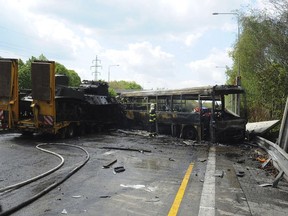 In this handout photo provided by Hasicsky Zachrany Sbor or HZS Praha, Czech Republic's firefighters investigate a scene of a crash in Prague, Czech Republic, Thursday, May 2, 2019. Czech firefighters and police say a bus with prisoners caught fire after colliding with two trucks, one of them carrying two tanks. The Prague rescue service says one person has died in the crash that occurred on Thursday on a busy ring road that leads to Prague's international airport. (HZS Praha via AP)