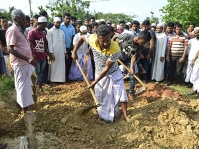 Sri Lankan Muslim workers throw soil over the coffin of Fauzul Ameen, the victim of an anti-Muslim riots, during a burial ceremony in a Muslim cemetery in Nattandiya on May 14, 2019.