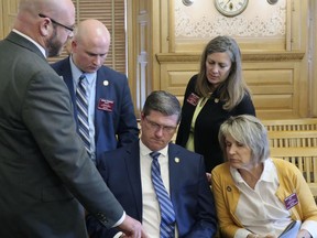 Kansas state Rep. Chris Croft, seated center, R-Overland Park, goes over a summary of a proposed $18.4 billion budget with colleagues after a meeting of GOP lawmakers, Friday, May 3, 2019, at the Statehouse in Topeka, Kan. Meeting with Croft, are from left, Reps. Stephen Owens, R-Hesston; Adam Thomas, R-Olathe; Kellie Warren, R-Leawood, and Barbara Wasinger, R-Hays,