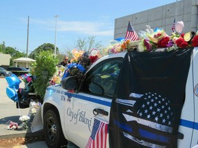 A Biloxi police vehicle that was assigned to patrolman Robert McKeithen is covered in flowers as Biloxi Police Capt. Milton Houseman, rear, talks , with a member of the Combat Veterans Motorcycle Association, Tuesday, May 7, 2019, in Biloxi, Moss. Houseman said he was one of the officers who brought Darian Tawan Atkinson, 19, to Biloxi after his arrest in Wiggins on May 6, in the death of Patrolman McKeithen.