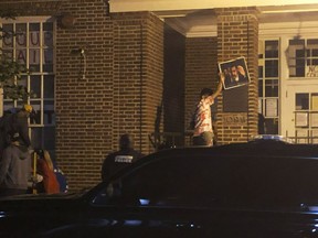 People remove posters from the front entrance of the Venezuelan Embassy in Washington on Monday, May 13, 2019. U.S. authorities have served an eviction notice to activists who have stayed for more than a month inside the Venezuelan embassy in Washington, and asked them to leave immediately.