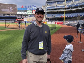 Michigan football coach Jim Harbaugh and his son, Jack, stand on the field at Yankee Stadium before the New York Yankees' baseball game against the Tampa Bay Rays on Friday, May 17, 2019, in New York. Shaking hands and posing for photos on the field during batting practice, Harbaugh wore a Yankees cap, a Michigan sweater vest and -- of course -- a crisp pair of khakis. He says he and his father had never been to Yankee Stadium before and it's a "bucket list" trip for them. Harbaugh, a lifelong baseball fan, grew up rooting for the Detroit Tigers while his father was an assistant coach under Bo Schembechler at Michigan.