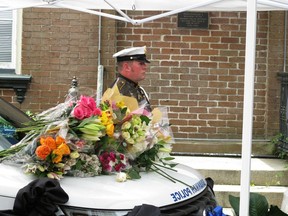 A Savannah police officer stands at attention next to a patrol SUV where law enforcement officers and local officials laid bouquets of flowers Monday, May 13, 2019, as a memorial to a slain patrol sergeant outside the police headquarters in Savannah, Georgia. Authorities say Sgt. Kelvin Ansari died after he was shot Saturday, May 11, 2019, while responding to an armed robbery outside a Savannah barber shot. A second officer survived after being shot in the leg. The suspect, Edward Fuller III, was shot and killed by police.