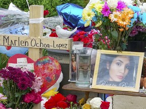 A memorial of flowers, balloons, a cross and photo of victim Marlen Ochoa-Lopez, are displayed on the lawn, Friday, May 17, 2019 in Chicago, outside the home where Ochoa-Lopez was murdered last month. Assistant State's Attorney James Murphy says a pregnant Ochoa-Lopez, who was killed and whose baby was cut from her womb, was strangled while being shown a photo album of the late son and brother of her attackers.