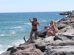 This May 21, 2018 photo shows beachgoers taking photos of each other on the rock jetty at the Manasquan, N.J. beach. On Friday, May 3, 2019, New Jersey Gov. Phil Murphy signed a law protecting the public's right to access and use the state's waterways and adjacent shorelines.