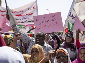 Protesters carry posters in Arabic that say, "Freedom, justice, and peace, and the revolution is the choice of the people," at the sit-in outside the military headquarters, in Khartoum, Sudan, Thursday, May 2, 2019. Sudan's protesters are holding a mass rally to step up pressure on the military to hand power to civilians following last month's overthrow of President Omar al-Bashir.