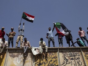 FILE - In this May 2, 2019, file photo, Sudanese protesters wave national flags at the sit-in outside the military headquarters, in Khartoum, Sudan. The satellite news channel Al-Jazeera said Friday, May 31, 2019, that Sudan shut down its bureau, just as the country's military government warned that the Khartoum sit-in that help bring ruler Omar al-Bashir's ouster had "become a threat to the revolution."
