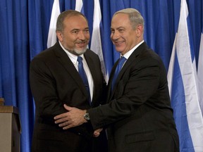 In this Oct. 25, 2012 file photo, Israeli Prime Minister Benjamin Netanyahu, right, and former Israeli Defense Minister Avigdor Lieberman shake hands in front of the media after giving a statement in Jerusalem.