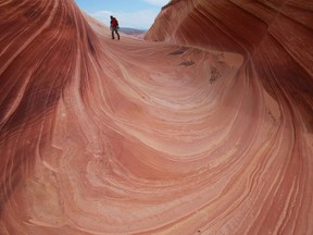 FILE - This May 28, 2013 file photo shows a on a rock formation known as The Wave in the Vermilion Cliffs National Monument in Arizona. A new proposal could mean bigger crowds at one of the most exclusive hiking spots in the southwestern United States. The Bureau of Land Management proposed changes Wednesday, May 8, 2019, that would increase daily visitor limits from 20 people to 96 people per day at The Wave, a popular rock formation near the Utah-Arizona border.